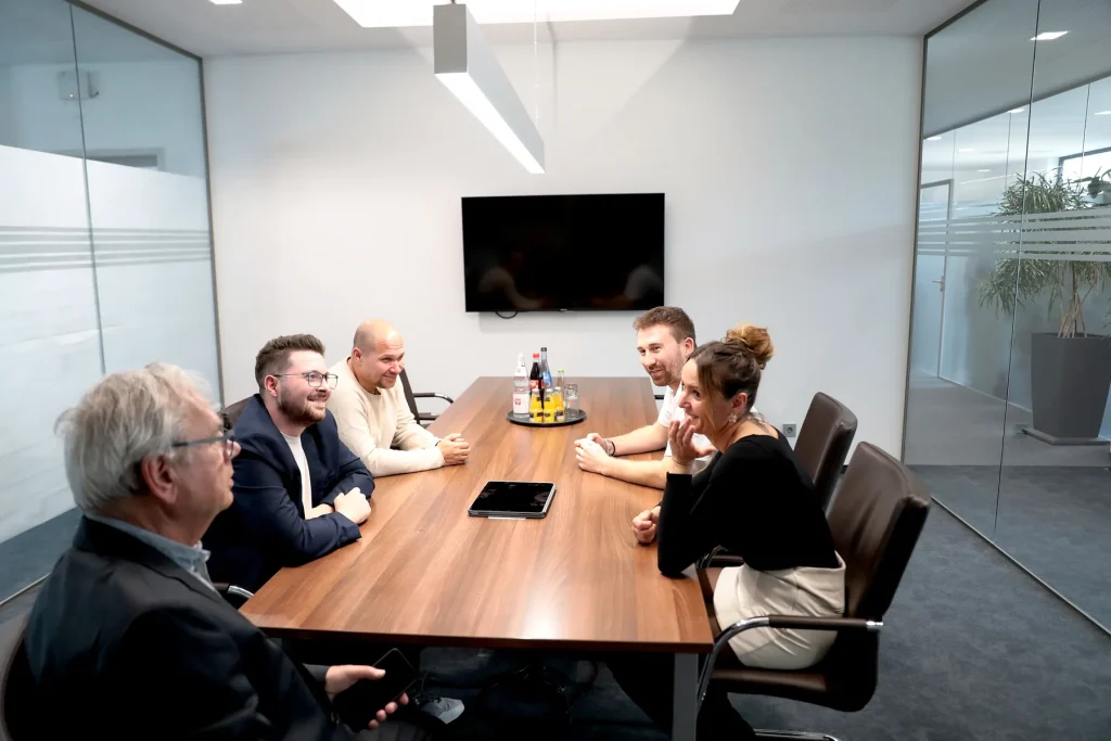 Sechs Personen bei einer Projektbesprechung am Konferenztisch im Büro